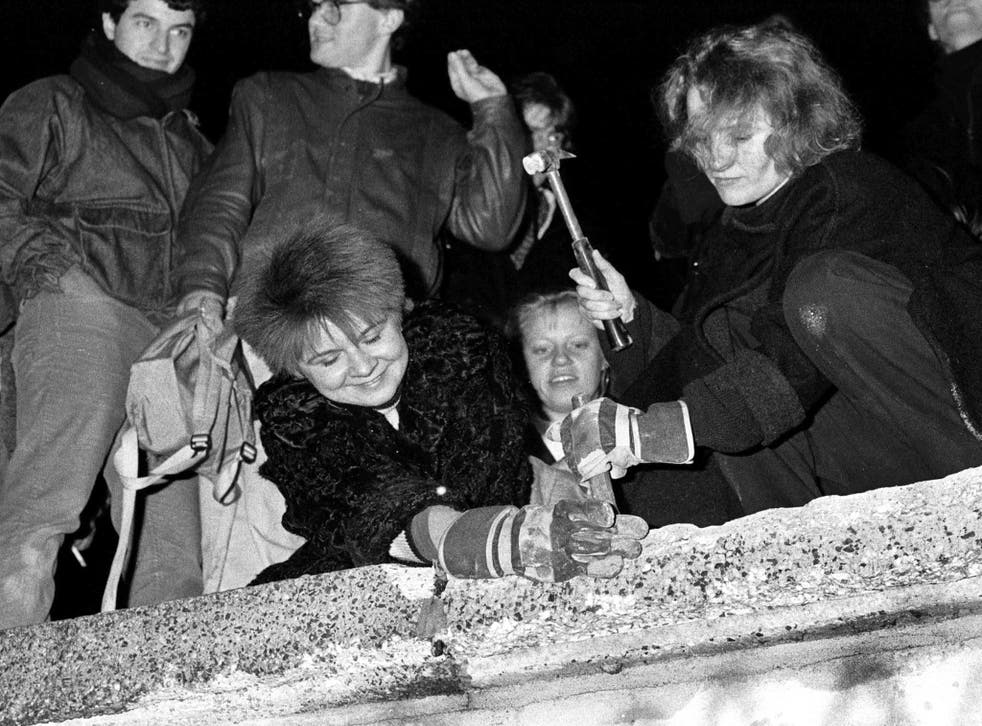 Berliners take a hammer and chisel to a section of the Berlin Wall in front of the Brandenburg Gate after the opening of the East German border was announced on 9 November 1989