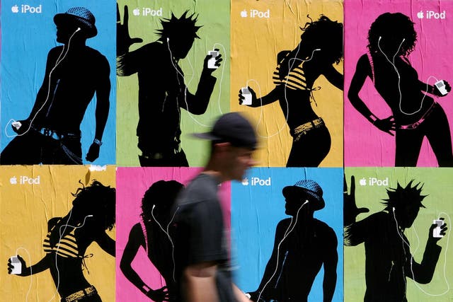 A pedestrian passes a wall covered with Apple iPod advertisements July 14, 2005 in San Francisco, California