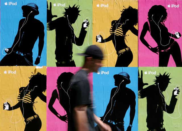 A pedestrian passes a wall covered with Apple iPod advertisements July 14, 2005 in San Francisco, California