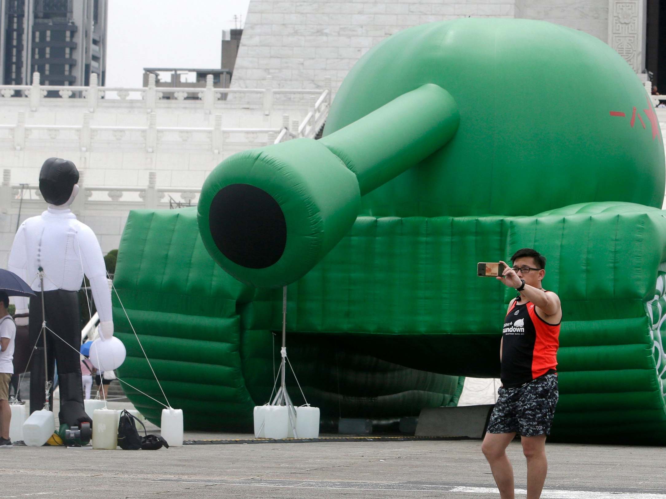 Taiwanese man takes a selfie with an inflatable tank installation in Taipei square
