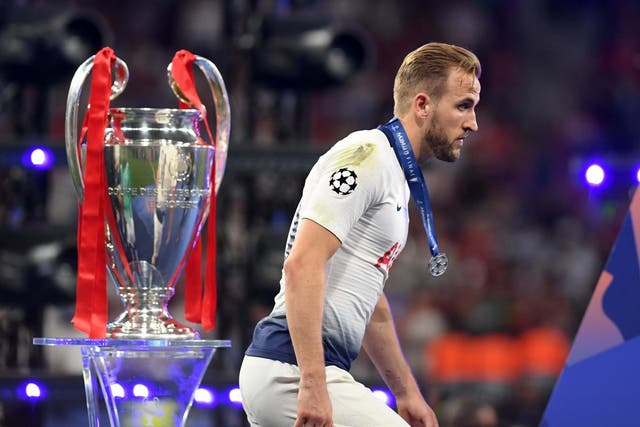 Harry Kane walks past the Champions League trophy