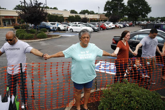 Lisa Dunaway, centre, of Virginia Beach, holds hands with other mourners during a vigil in response to a fatal shooting at a municipal building