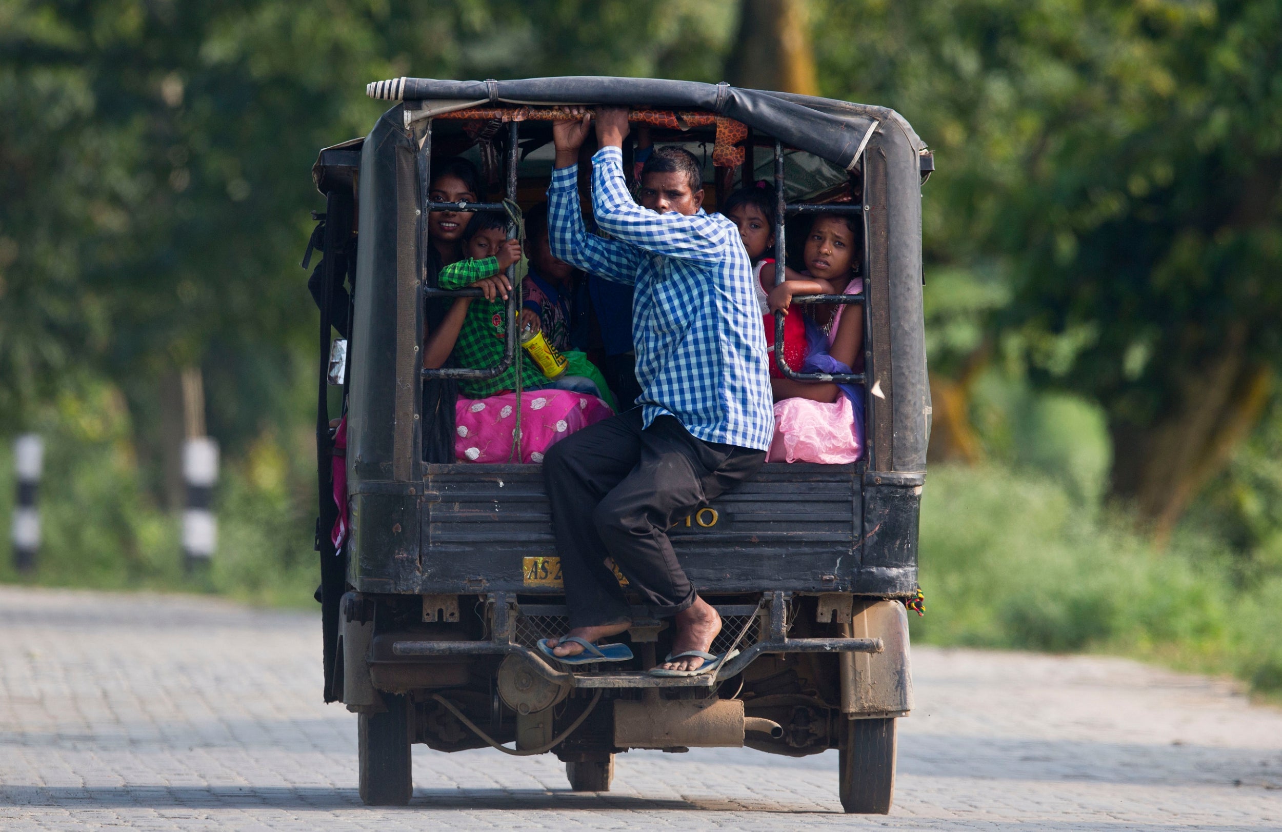 Indian passengers travel on an auto rickshaw on the outskirts of Gauhati, India