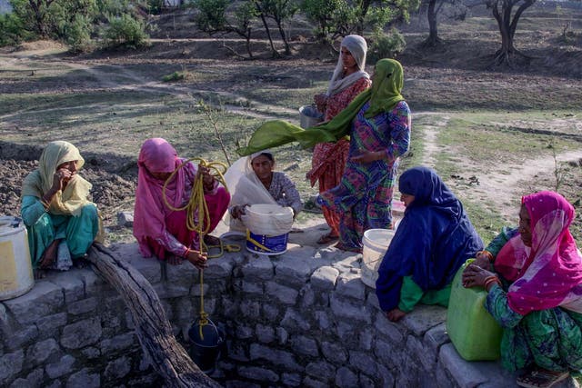 Indian villagers try to gather water from a well running dry in searing heat near Jammu
