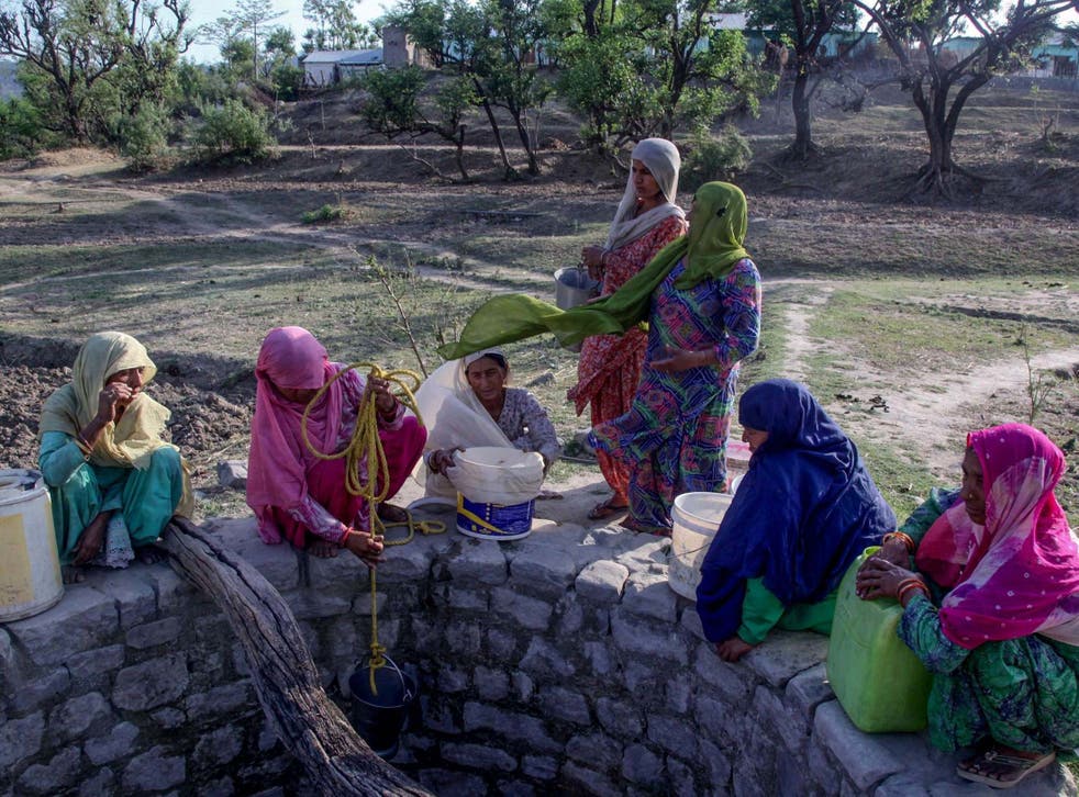 Indian villagers try to gather water from a well running dry in searing heat near Jammu