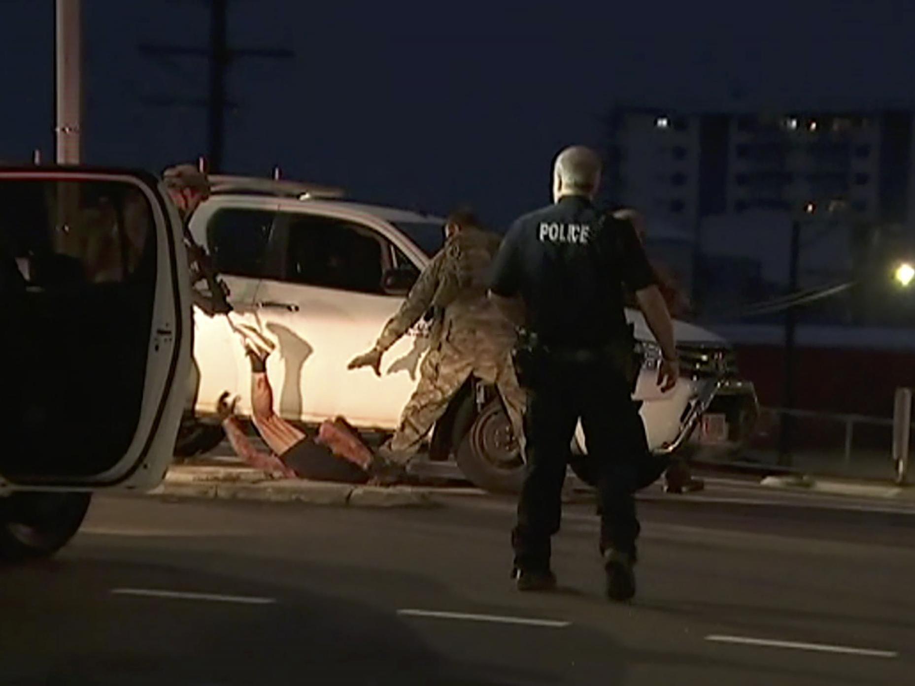 In this image made from video, police proceed to apprehend a suspect on the ground next to a white truck on Tuesday 4 June, in Darwin, Australia.