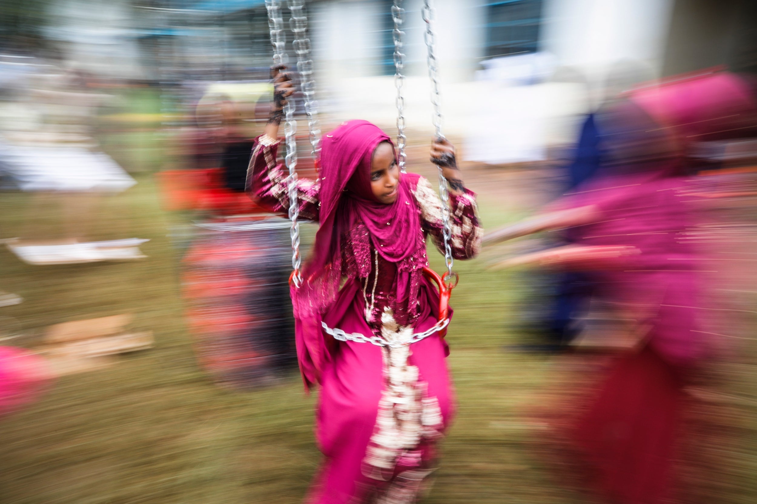 A young Muslim girl enjoys a swing ride during an Eid celebration