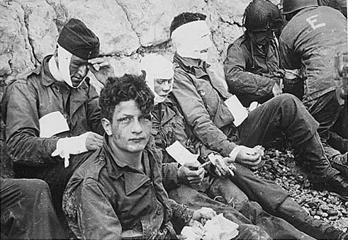 Wounded while storming Omaha Beach on D-Day, soldiers waiting by the chalk cliffs for evacuation to a field hospital for treatment (The US army)