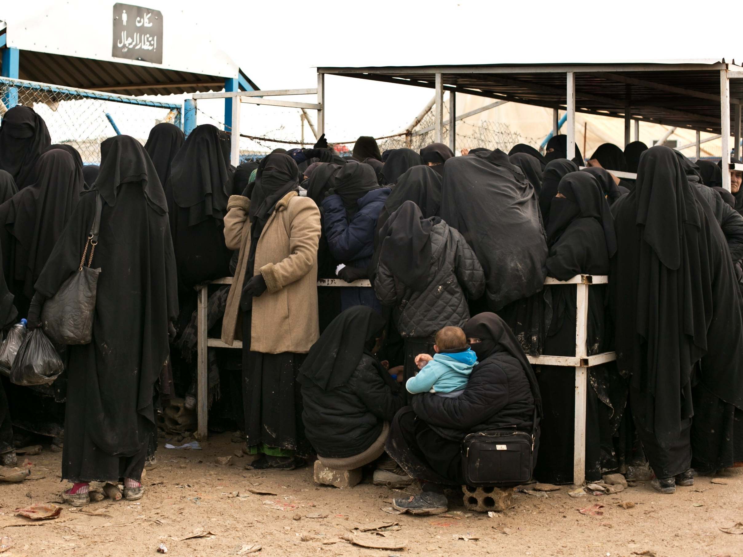Women wait for aid at al-Hol refugee camp, the largest in Syria