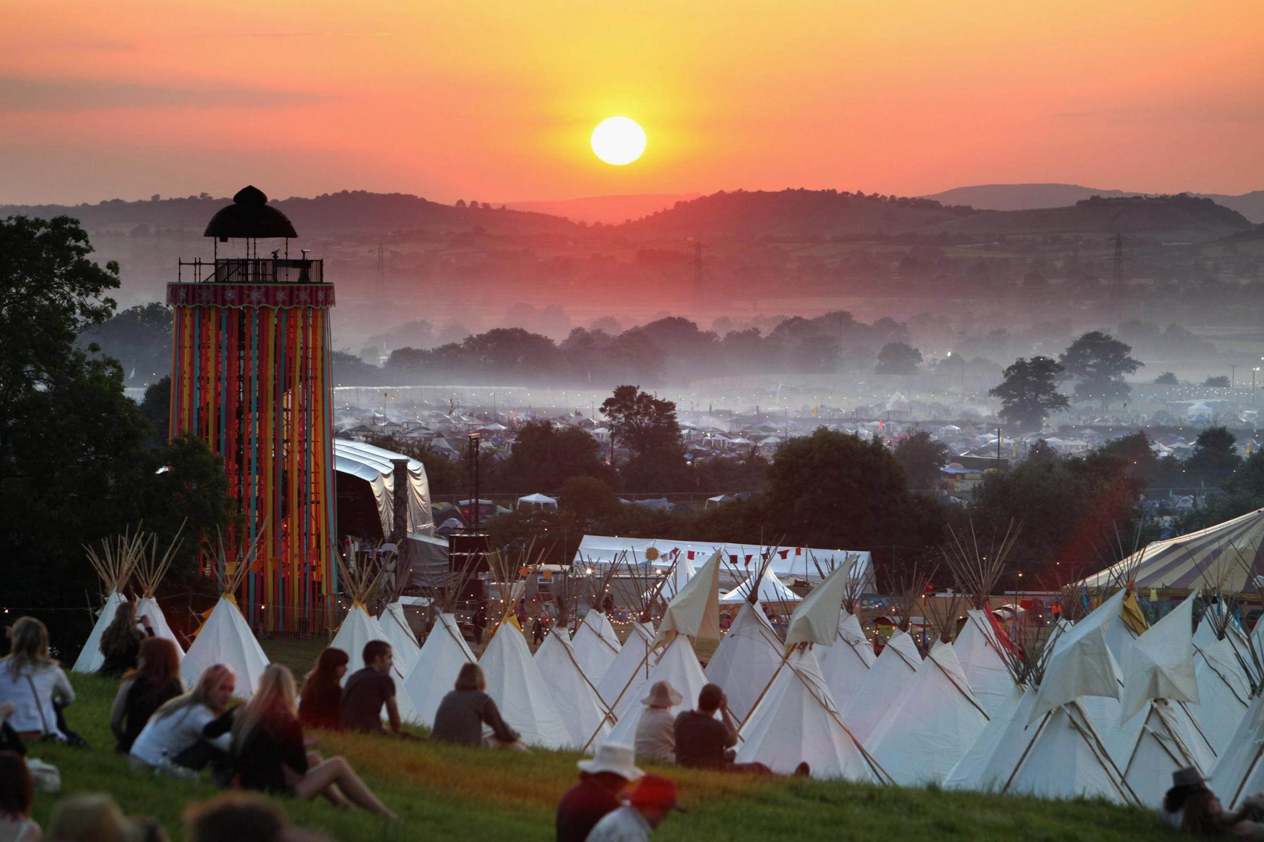 People gather to watch the sunset on a hill above the tipi field at Glastonbury in 2009