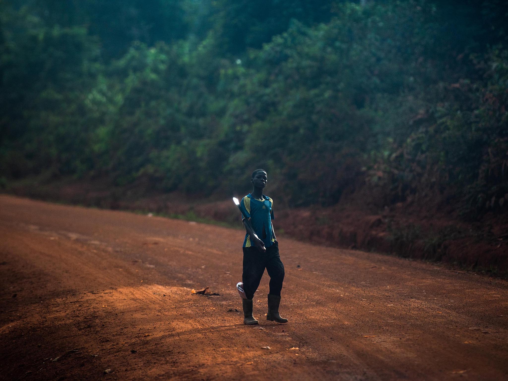 A boy holds a machete on his way to a farm