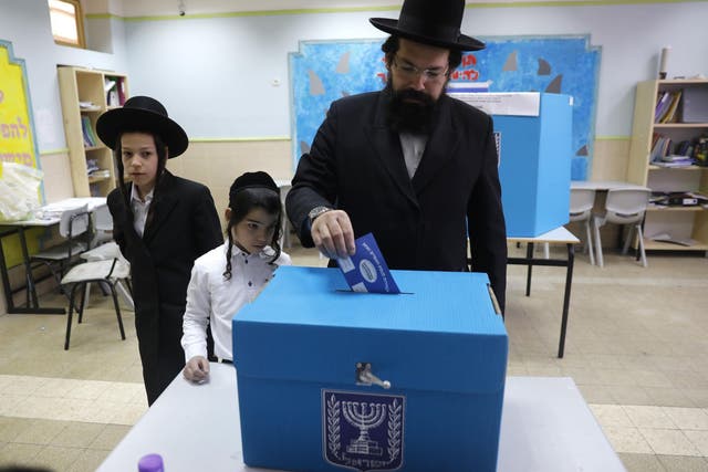 Children watch a Haredi Jewish man cast his vote in Jerusalem during Israel’s parliamentary elections in April