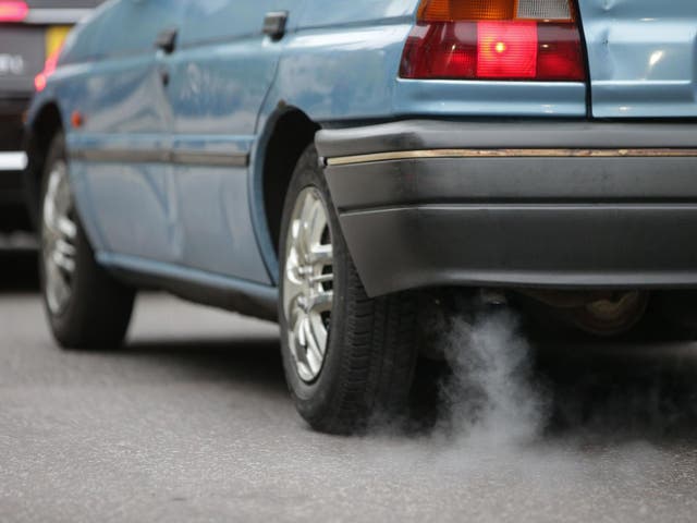 A car emits fumes from its exhaust as it waits in traffic in central London