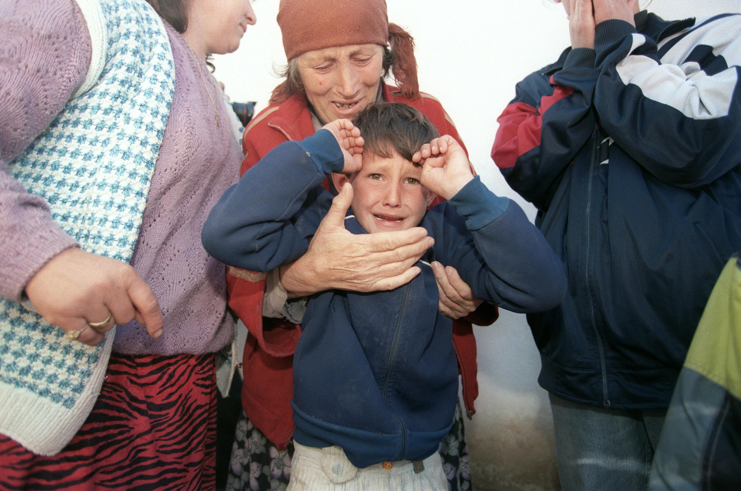 An elderly ethnic Albanian refugee woman from the village of Donje Prekaze in Kosovo holds her crying grandson as they hide from Serbian police in 1998