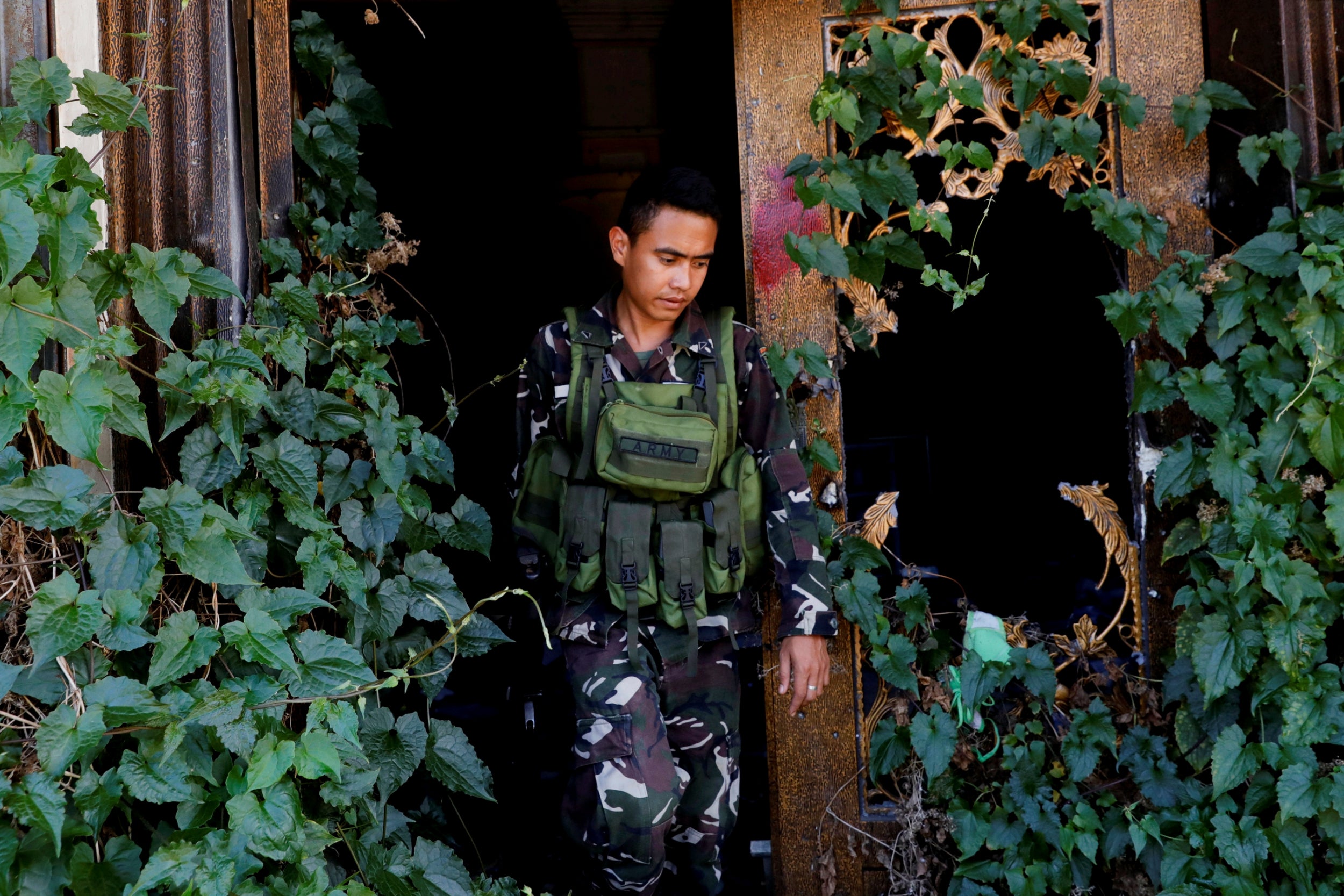 A government soldier walks out of a crumbling structure