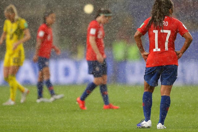 Players from Chile and Sweden stand in the heavy rain in Rennes