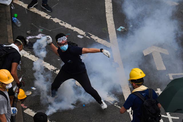 A protester throws back a tear gas during clashes with police outside the government headquarters in Hong Kong on June 12, 2019