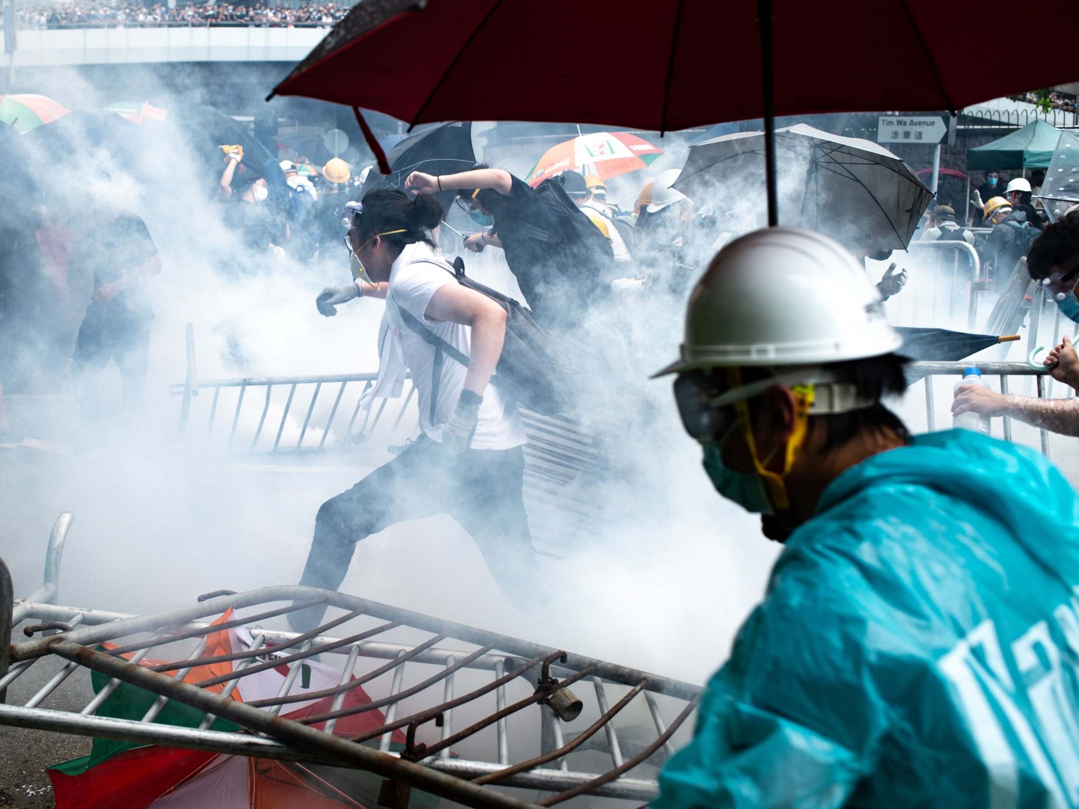 Protesters run after police fired tear gas during a rally against a controversial extradition law proposal outside the government headquarters in Hong Kong