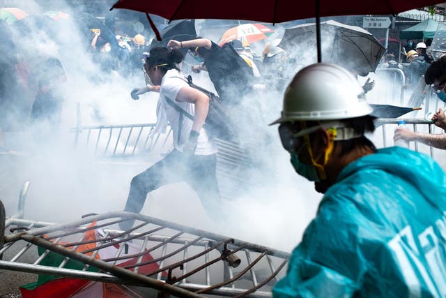Protesters run after police fired tear gas during a rally against a controversial extradition law proposal outside the government headquarters in Hong Kong