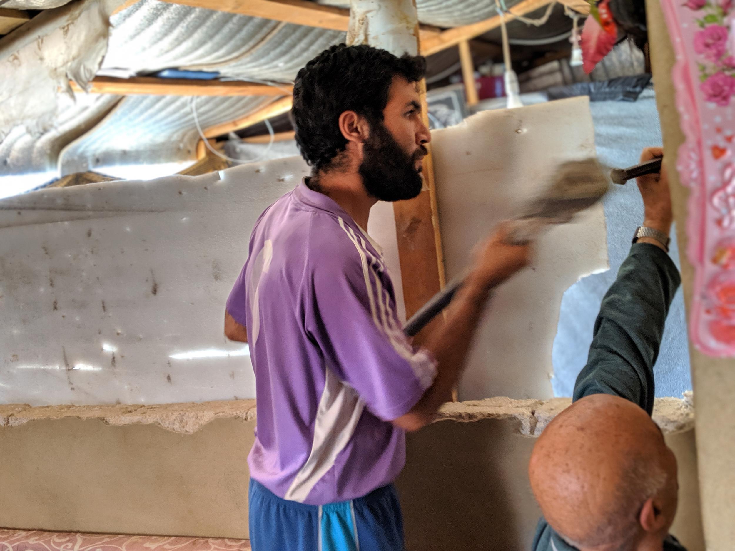 Salah Mustafa, a 35-year-old Syrian refugee from the outskirts of Damascus who fled to Lebanon five years ago, takes a hammer to the concrete walls of his shelter at a camp in the Lebanese town of Arsal