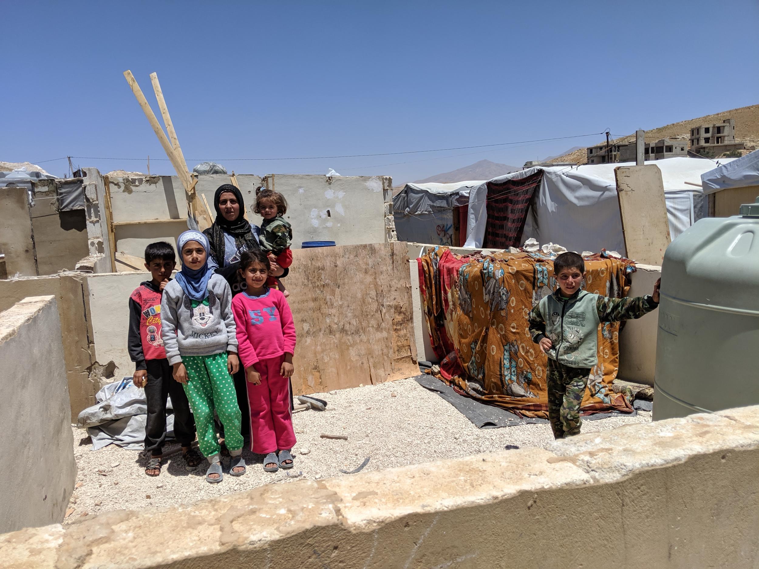 Fatimah Hammoud, 25, stands with her children in the remains of her shelter. Her husband removed the roof to stop it being demolished entirely (Richard Hall/The Independent)