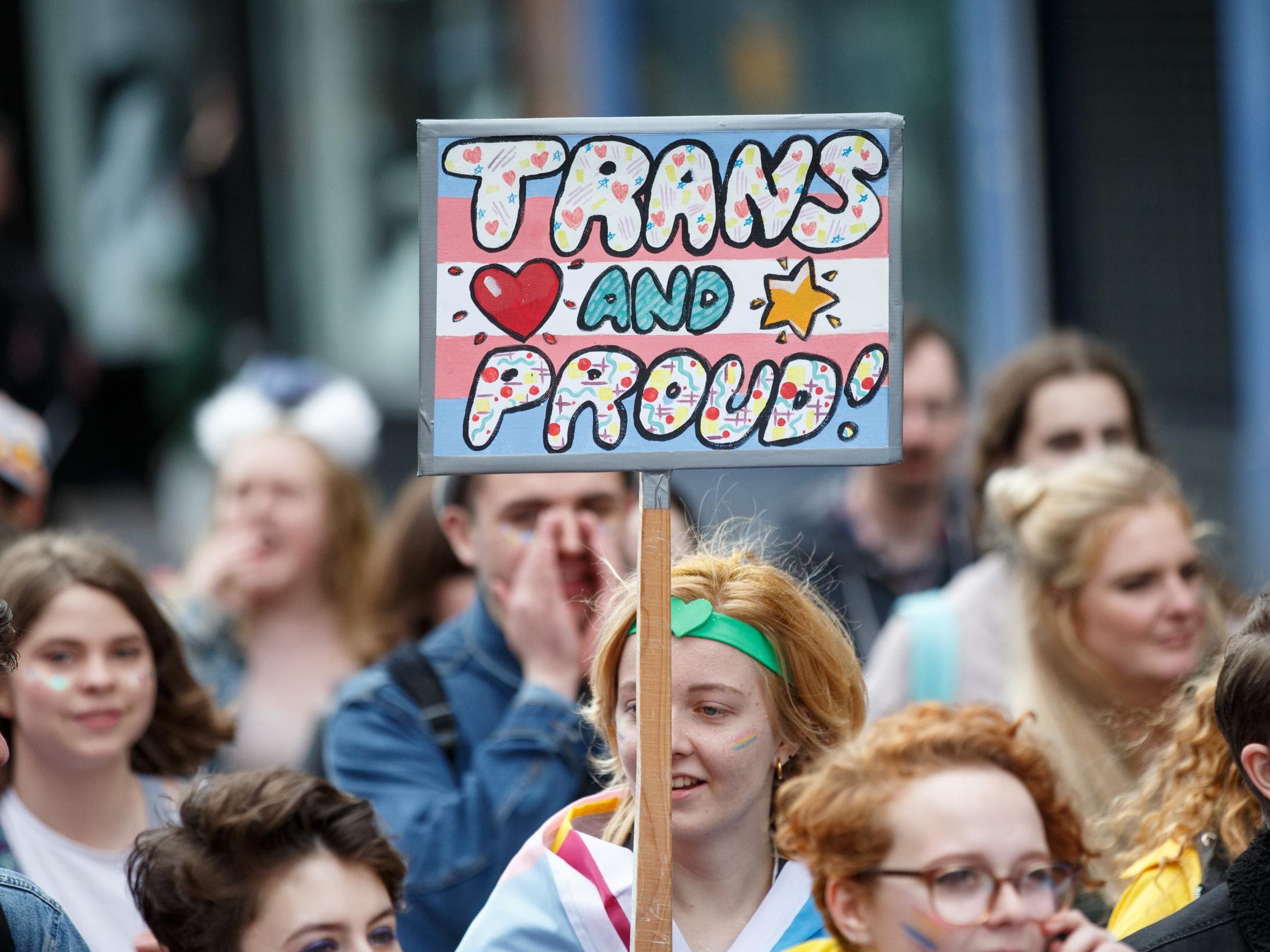 An individual holds a sign saying 'Trans and Proud' during Glasgow Pride 2017