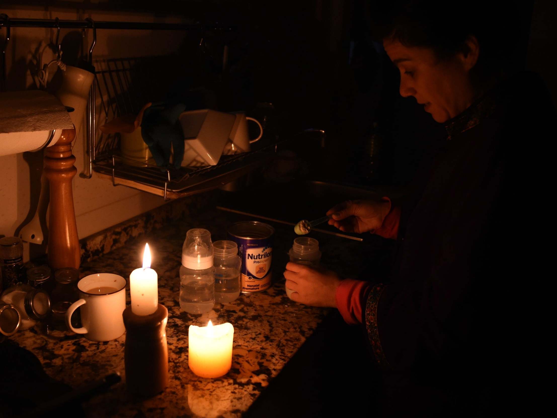 A woman cooks using candelight during the power cut