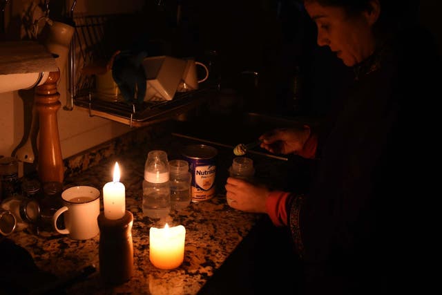 A woman cooks using candelight during the power cut