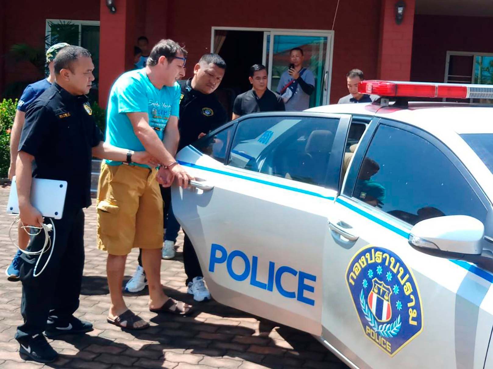 Italian jail escapee Francesco Galdeli, who used George Clooney's name to con investors, is detained by Thai police officers at a house in Chonburi
