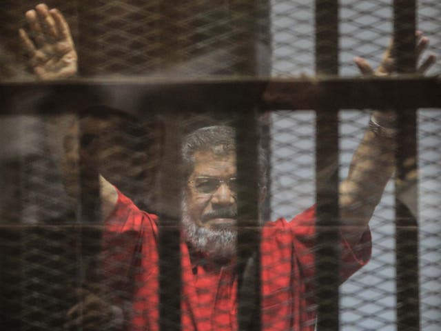 Ousted Egyptian President Mohamed Morsi gestures during a trial session on charges of espionage in Cairo, Egypt