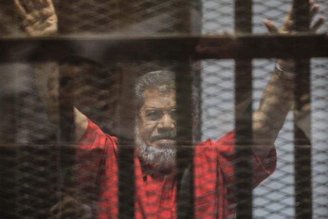 Ousted Egyptian President Mohamed Morsi gestures during a trial session on charges of espionage in Cairo, Egypt