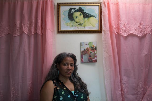 <p>Rosa Hernandez stands beneath a picture of her dead daughter Rosaura Almonte Hernandez who doctors initially blocked from having chemotherapy as she was pregnant</p>