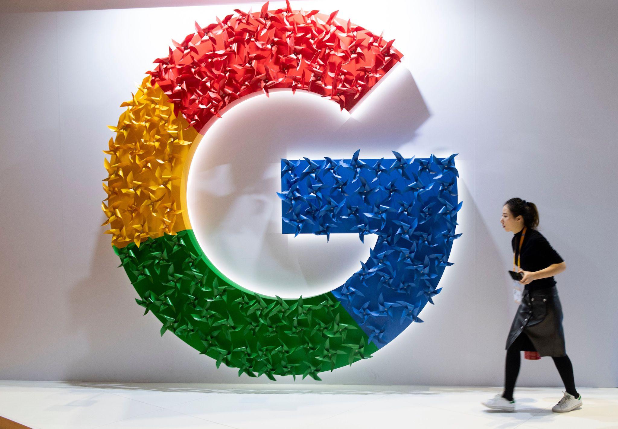 This picture taken on November 5, 2018 shows a woman passing a booth of Google at the first China International Import Expo (CIIE) in Shanghai