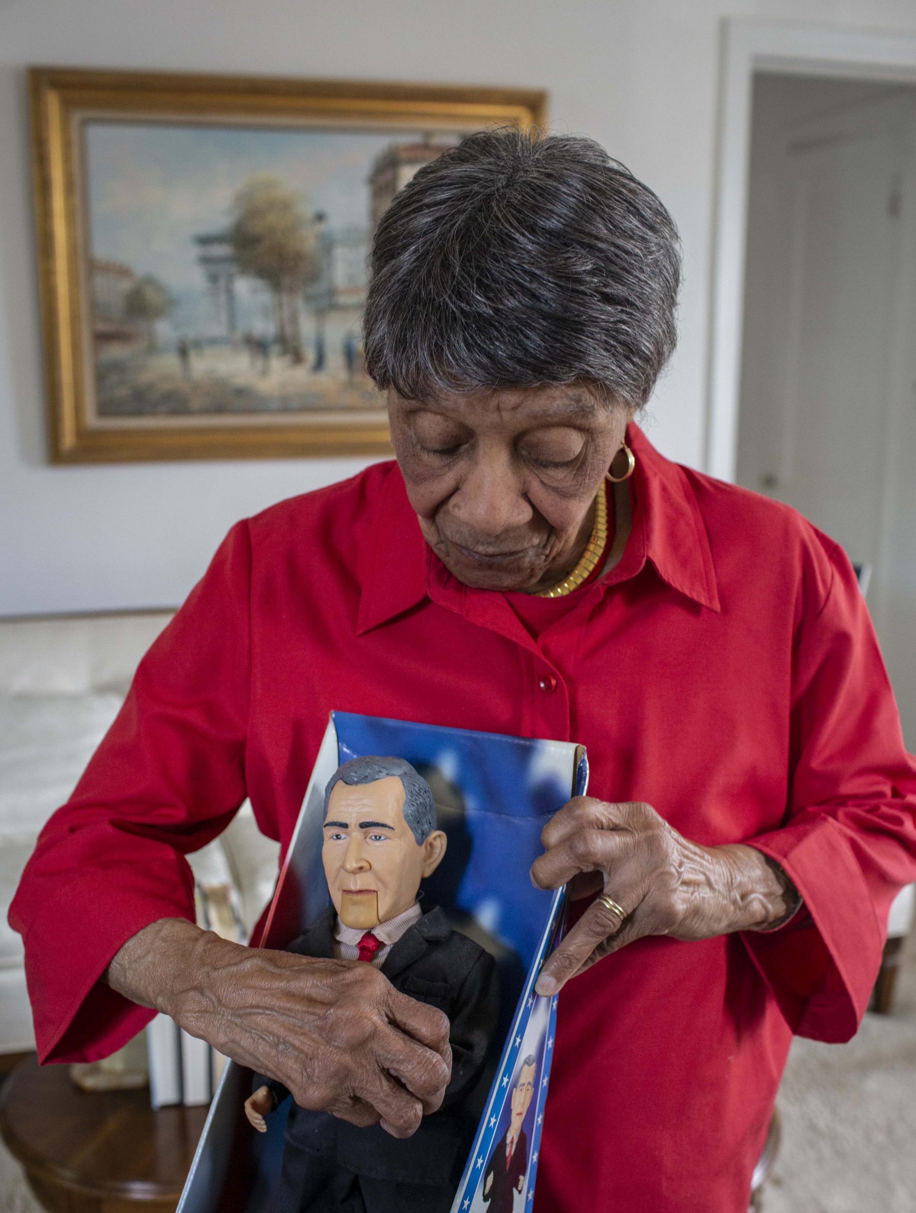 Louise Griffin, 99, a retired teacher and principal who has volunteered at the White House for 26 years, holds a singing caricature of George W Bush