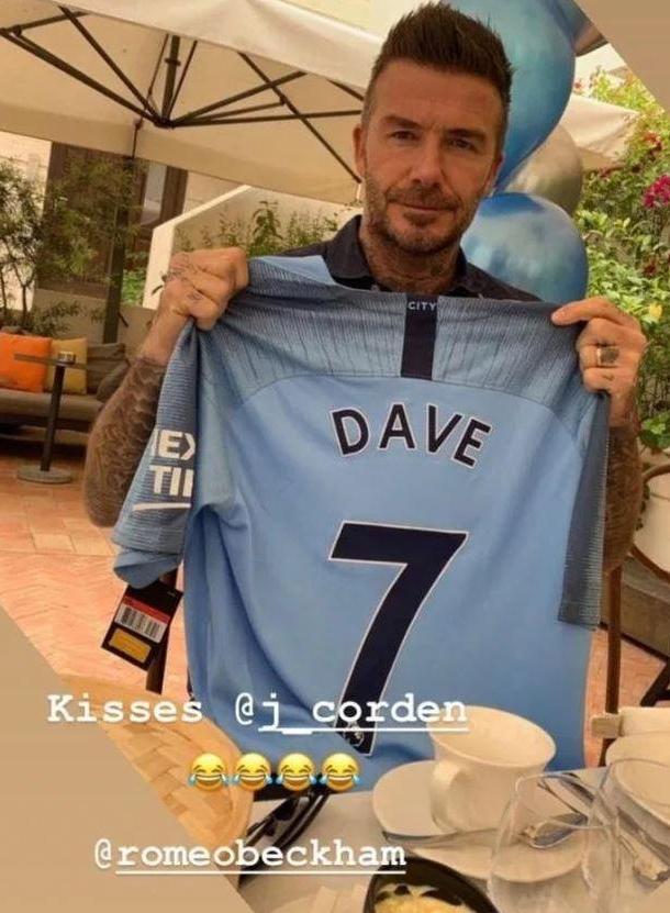 Beckham is shown holding up a Manchester City shirt