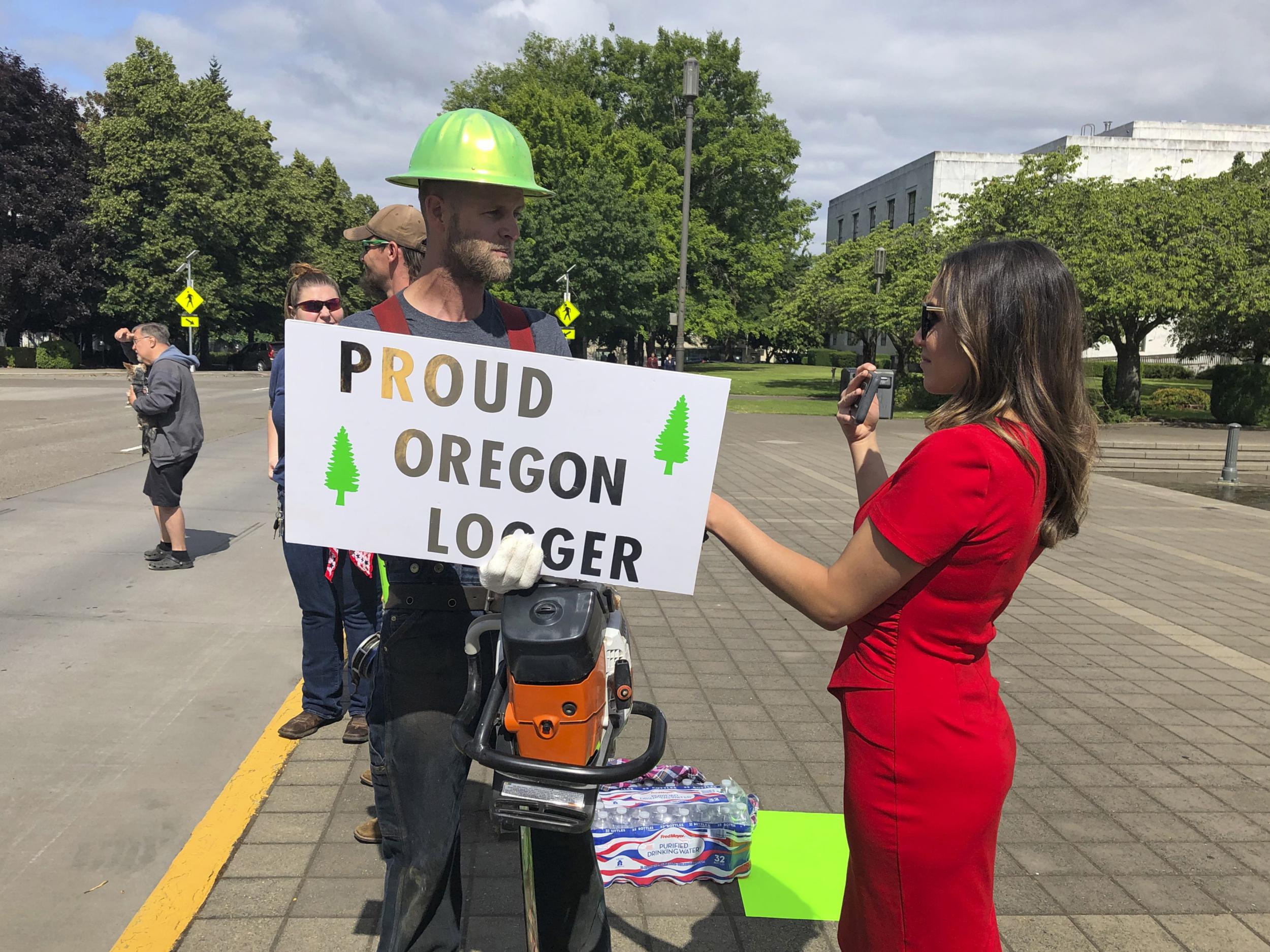 A TV reporter interviews self-employed logger Bridger Hasbrouck, of Dallas, Oregon