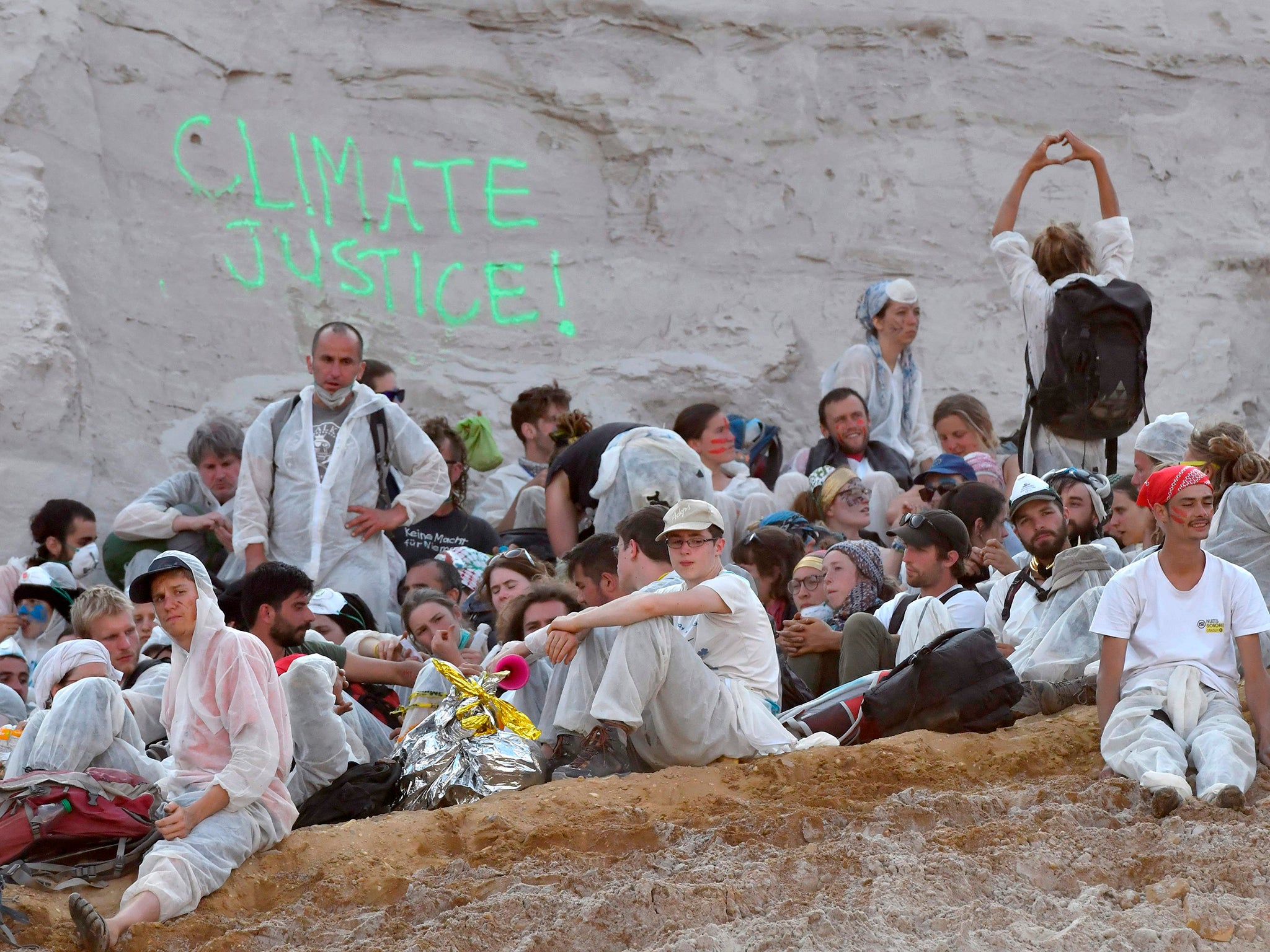 Climate activists sit on the ground after breaking through a police cordon and entering the Garzweiler coal mine in western Germany