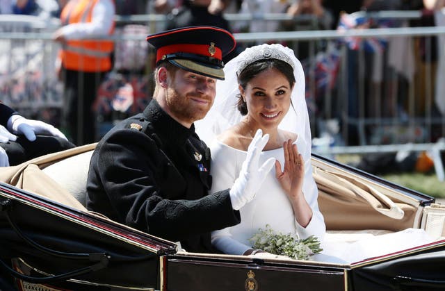 Prince Harry, Duke of Sussex and Meghan, Duchess of Sussex wave from the Ascot Landau Carriage during their carriage procession on Castle Hill outside Windsor Castle in Windsor, on May 19, 2018 after their wedding ceremony.