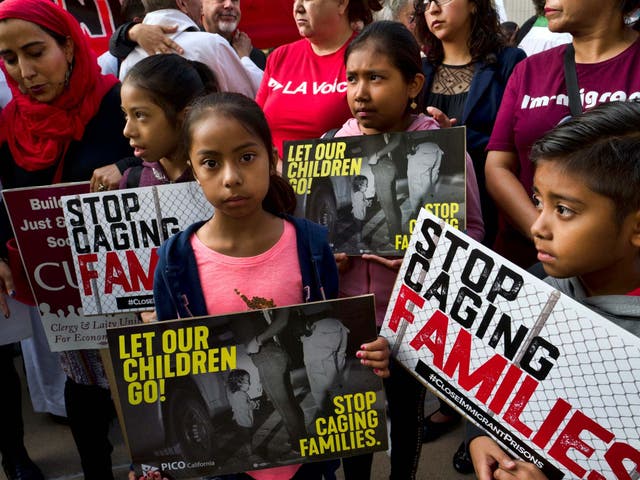 Children stand and hold protest signs during a rally in front of Federal Courthouse in Los Angeles