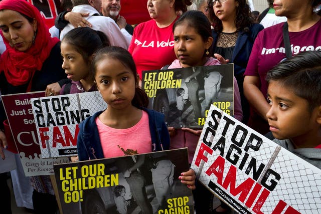 Children stand and hold protest signs during a rally in front of Federal Courthouse in Los Angeles