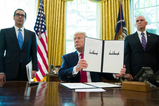 President Donald Trump holds up an executive order to increase sanctions on Iran, in June 2019. He is pictured with Steve Mnuchin, left, and Vice President Mike Pence. The US has now granted Iran a sanctions waiver for humanitarian trade