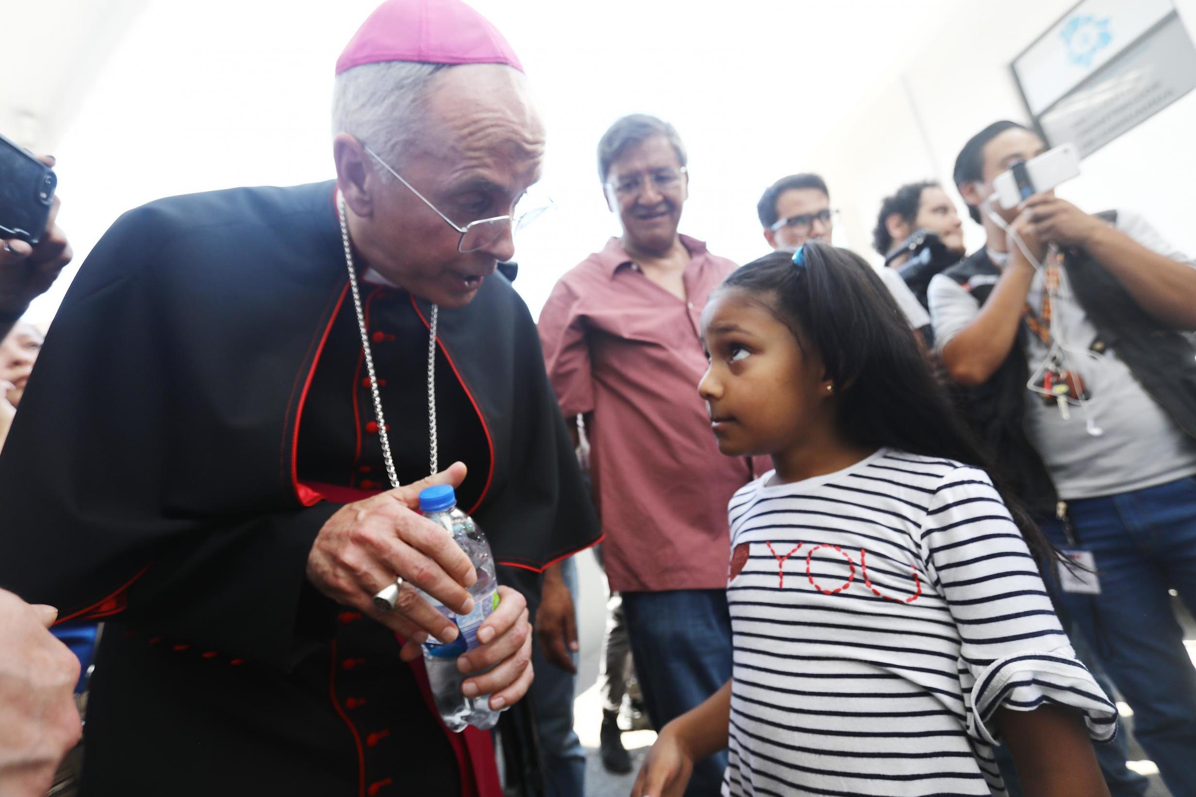 El Paso Bishop Mark Seitz prepares to escort a 9-year-old Honduran girl before they cross a border entry bridge into the US.