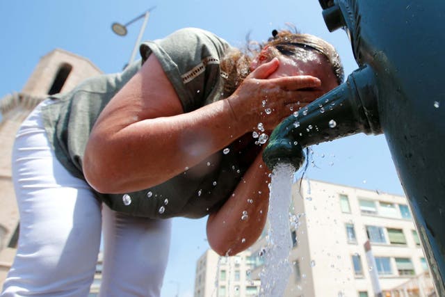 A woman cools off in a water fountain in Marseille as heatwave hits France