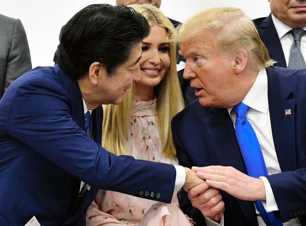 President Trump takes Shinzo Abe's hand as he tries to tell him something at the G20 summit