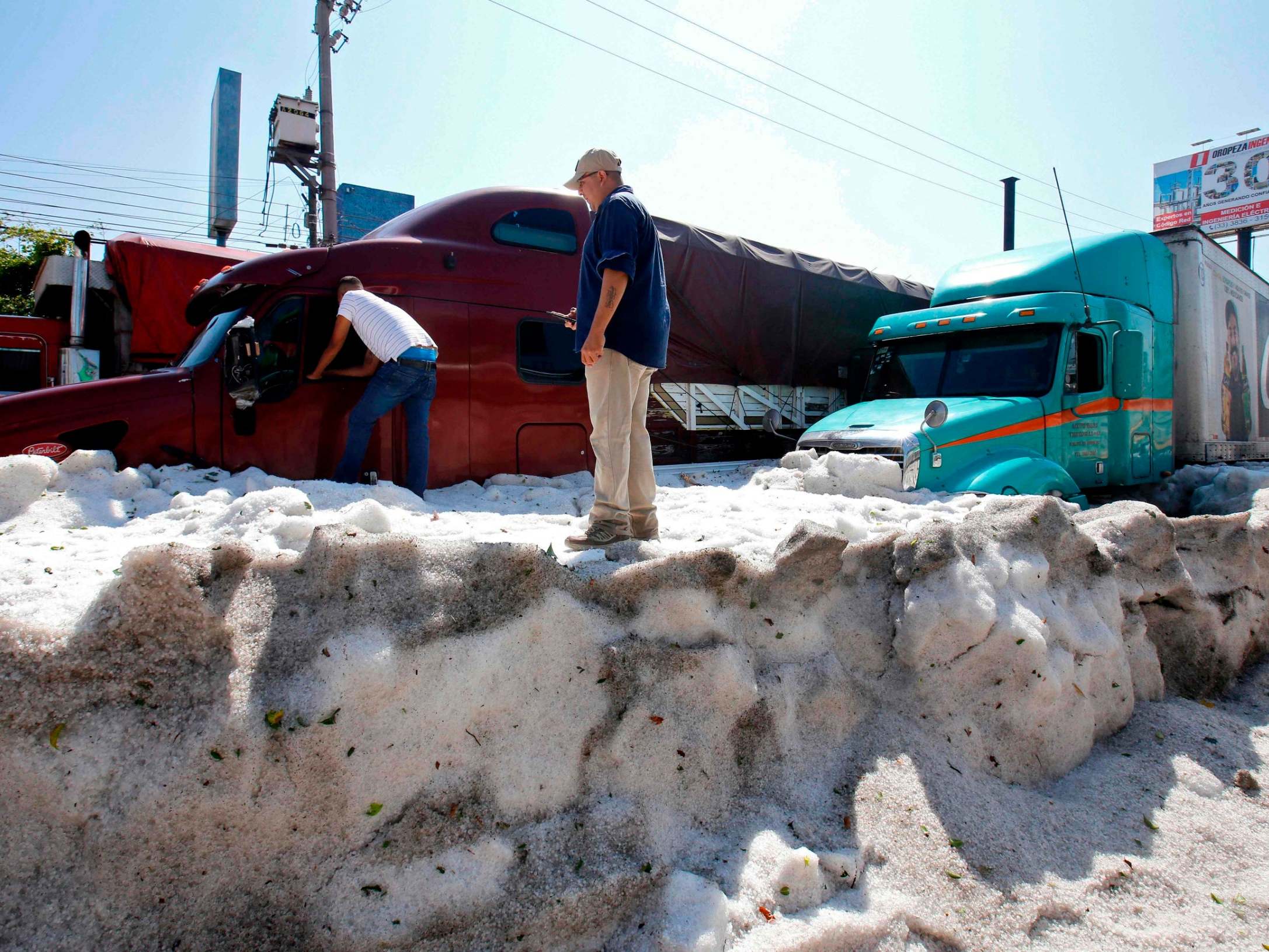 Men remain next to trucks buried in hail in the eastern area of Guadalajara, Jalisco state, Mexico