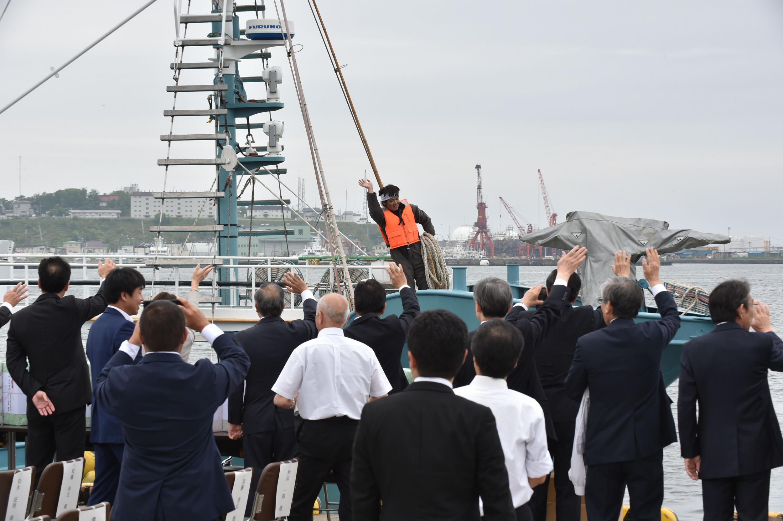 A fisherman waves to well-wishers on a whaling ship as they depart from a port in Kushiro, Hokkaido