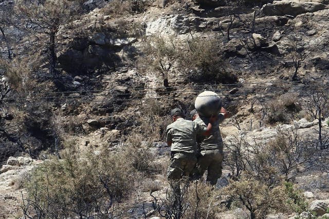 Military personnel carry debris on a slope where a missile struck, in Tashkent (also known as Vouno), in northern Cyprus, 1 July 2019.