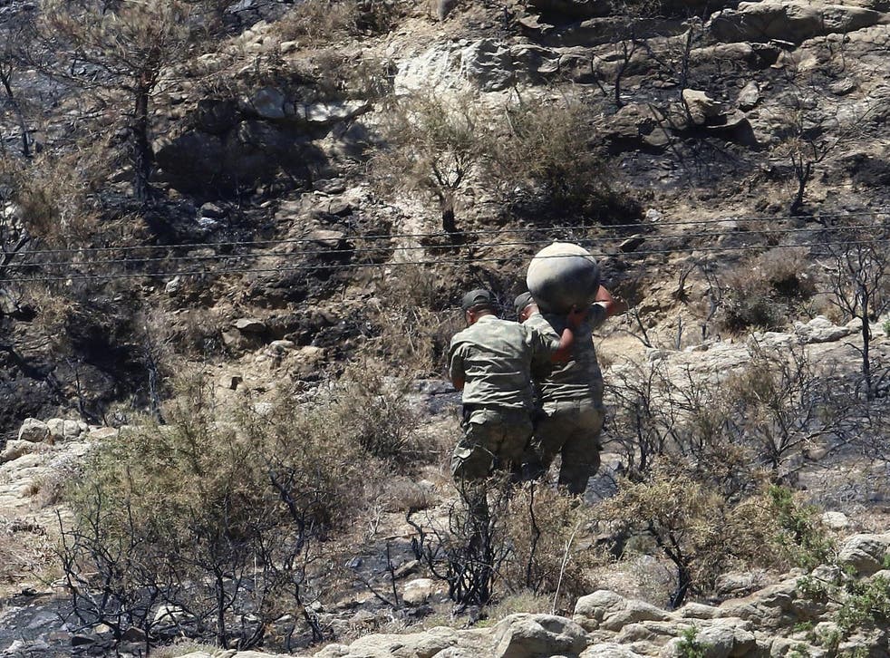 Military personnel carry debris on a slope where a missile struck, in Tashkent (also known as Vouno), in northern Cyprus, 1 July 2019.