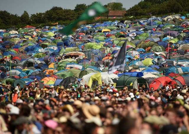 Festival-goers' tents spread out on the hillside behind crowds