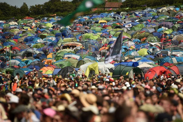Festival-goers' tents spread out on the hillside behind crowds